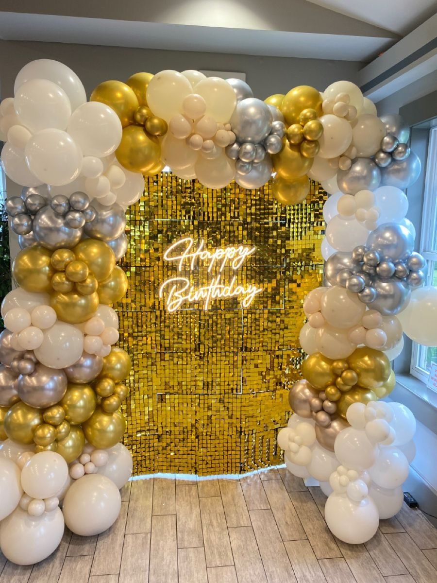Birthday party balloon decoration with gold and white arch
